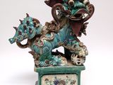 statue of a dragon with a ball in its mouth on a pedestal