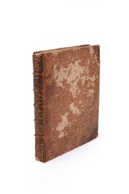 an old book with a brown cover sitting on top of a white surface