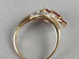 a close up of a gold ring with a diamond and a ruby stone
