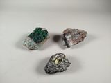 three pieces of rock with green and yellow crystals on a white surface