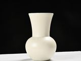 a white vase sitting on a table with a black background
