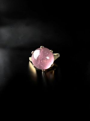 a close up of a pink stone ring on a black surface