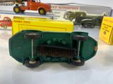 a green toy truck with a broom on top of it