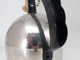 a silver kettle with a black handle on a white table