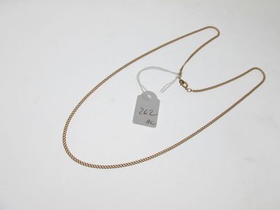 a gold chain with a tag attached to it on a white surface