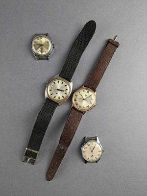 three different types of watches on a gray surface with a black strap