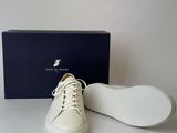 white leather sneakers with white laces and a blue box on a white surface