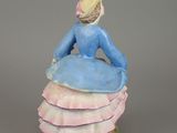 a figurine of a woman sitting on top of a stack of plates