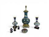 trois vases bleus et dorés et une lampe posés sur une surface blanche