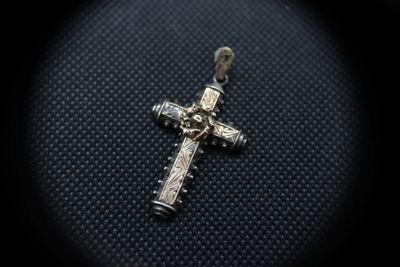 a close up of a silver cross on a black background