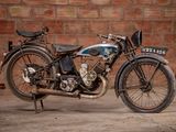 a old motorcycle that is parked in front of a brick wall