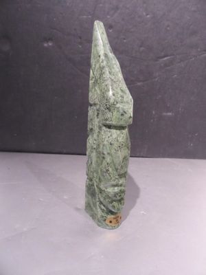 a close up of a green stone statue on a white surface