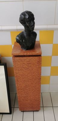 a statue of a dog sitting on top of a wooden pedestal