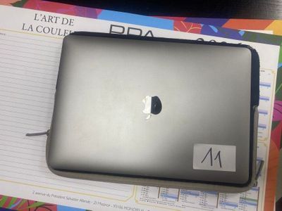 un ordinateur portable Apple posé sur un cahier, sur une table