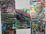 Des cartes du jeu de cartes Pokémon sont alignées sur une surface blanche