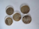 six different british coins in plastic containers on a white surface