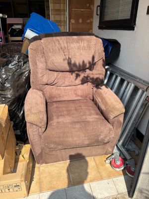 un fauteuil inclinable marron posé au milieu d'une pile de cartons