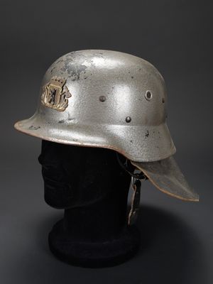 un vieux casque posé sur la tête d'un mannequin, sur fond gris