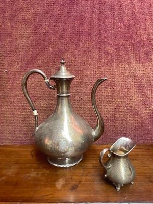 une théière en argent et une théière en argent posées sur une table en bois
