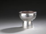une coupe en argent posée sur une table, sur fond noir