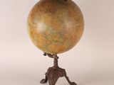 an antique globe on a tripod stand on a white background