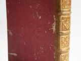 un vieux livre posé sur une table blanche à côté d'un mur blanc