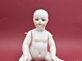 une petite poupée blanche assise par terre sur un fond rouge