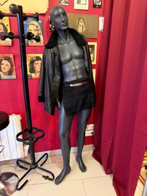 un mannequin dans une pièce où il y a des tableaux accrochés au mur