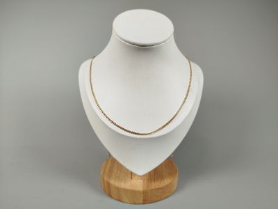a close up of a necklace on a wooden stand on a gray background