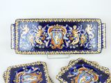 three pieces of blue and gold decorated plates on a table