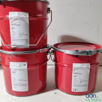 trois seaux de peinture rouge posés sur un plan de travail blanc