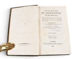 an open book on a white surface with a gold hand resting on top of it