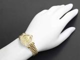 a woman ' s hand with a gold watch on it ' s wrist