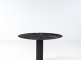 une table ronde avec un plateau en marbre noir sur fond blanc