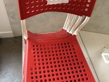 une chaise en plastique rouge sur laquelle est accrochée une étiquette de prix