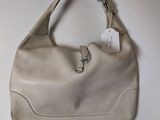 beige leather handbag hanging on a white wall with a tag attached to it