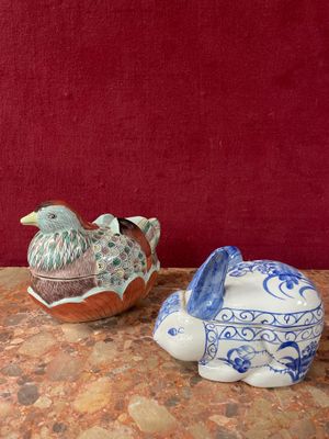 two ceramic animals sitting on a table next to a red wall