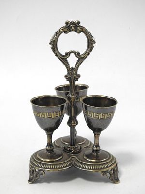 a silver plate with three cups on it on a stand