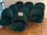 six chaises en velours vert aux pieds dorés dans une pièce