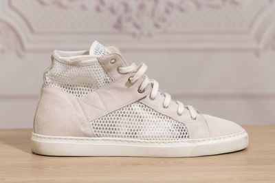 white high top sneakers on a wooden table with a wallpaper in the background