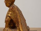 an antique bronze figurine of a boy sitting on the ground