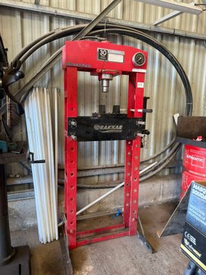 une photo d'une presse hydraulique rouge dans un garage