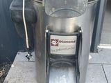 une poubelle en métal posée sur le trottoir, à côté d'un immeuble