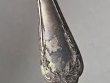a silver spoon with a silver handle hanging from it ' s side