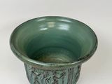a green bowl with a design on it on a white surface