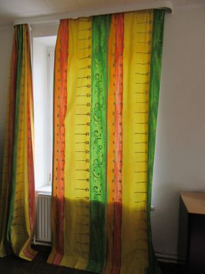 des rideaux jaunes et verts dans une pièce équipée d'un bureau et d'une fenêtre