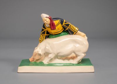 figurine of a man riding a pig on a green base