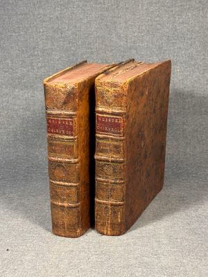 two old books are sitting on a table with a gray background