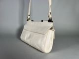 the small white purse is sitting on a gray surface