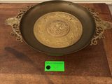 a gold plate on a wooden table with a green tag on it